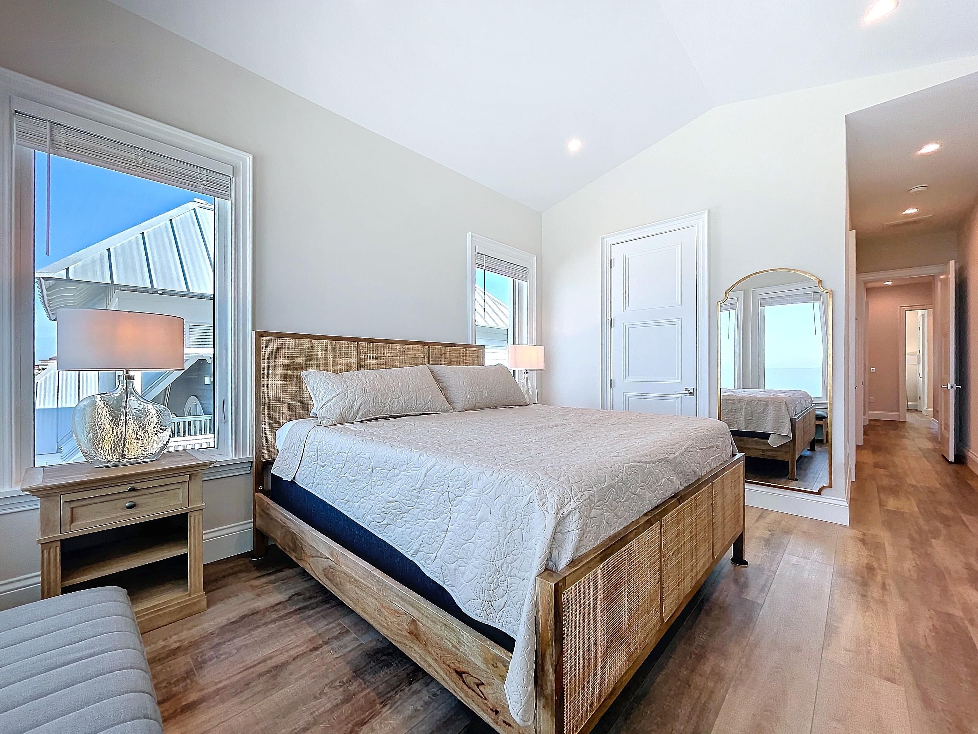 Un dormitorio con una cama grande, una mesita de noche, una lámpara y una ventana con persianas.