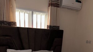 A bed with white bedding, a brown headboard, and a decorative pillow. - Beach Side Shortlet Apartment Lekki (Lekki)