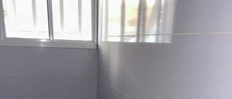 A bathroom with a toilet and sink, tiled walls, and a window.