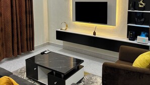 A modern living room with a flat-screen TV, a black console table, a sofa, and a coffee table. - Beach Side Shortlet Apartment Lekki (Lekki)