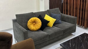 A living room with a grey sofa, yellow and black cushions, a black coffee table, and a painting of a ship on the wall. - Beach Side Shortlet Apartment Lekki (Lekki)