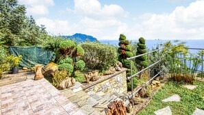 Un jardin agrémenté d’un escalier en pierre, de différentes plantes et d’une rambarde métallique surplombant une étendue d’eau.