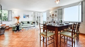 Un vaste espace de vie comprenant une table à manger pour six personnes, un canapé et une vue sur l’extérieur.
