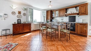 Une cuisine spacieuse avec des meubles en bois, une table à manger avec des chaises et une grande fenêtre qui laisse entrer la lumière naturelle.
