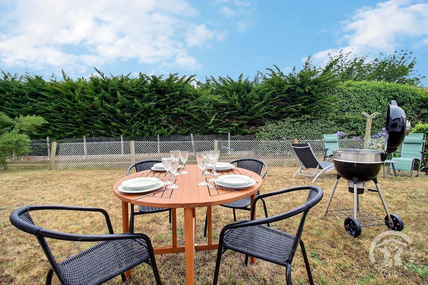 An outdoor dining area with a round table set for four, surrounded by wicker chairs.