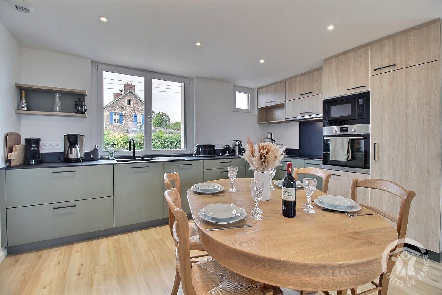 A modern kitchen with grey cabinets, a wooden dining table, and a view of the outside.