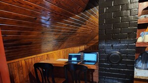 Een kamer met houten lambrisering, een bakstenen muur, een tafel met twee laptops en twee stoelen.