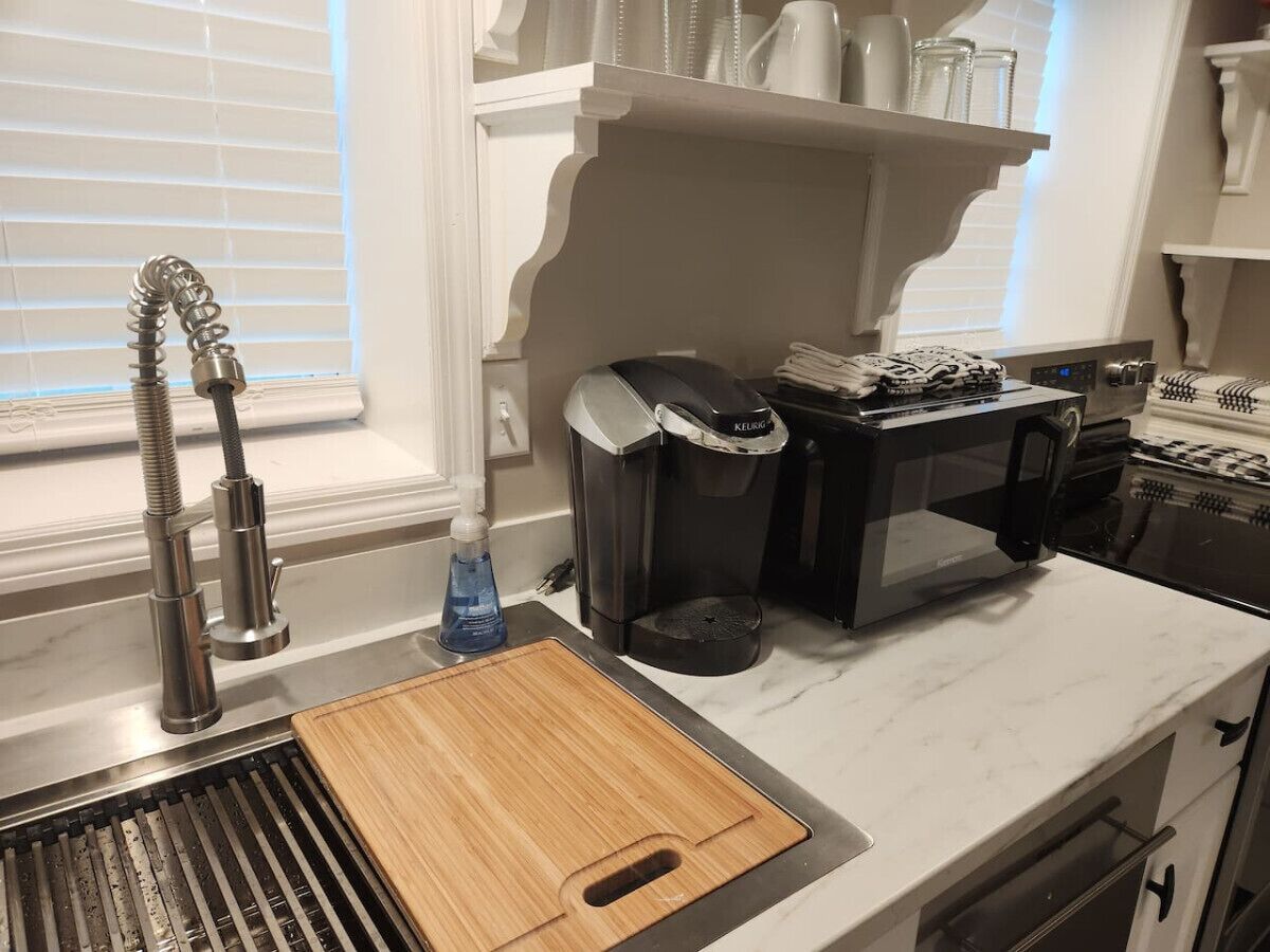 A kitchen with a modern stainless steel sink, a coffee maker, and a microwave.