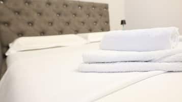 A neatly made bed with white linens and a folded white towel on top.