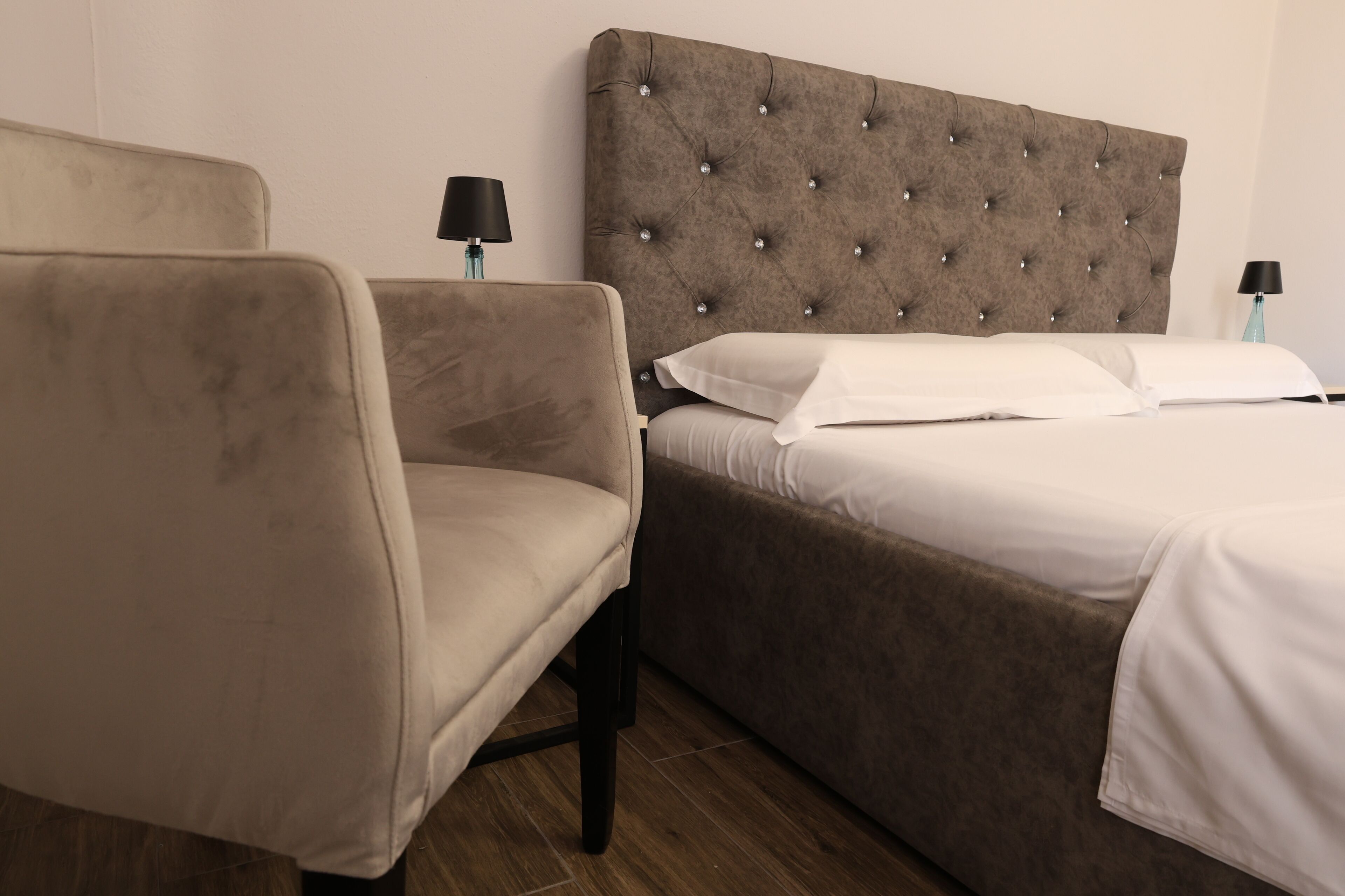 A hotel room with a bed, a chair, and two bedside lamps.