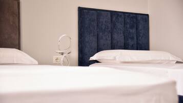 Habitación de hotel con una cama grande, una mesita de noche con lámpara y un enchufe.