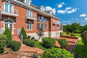 A large brick building with multiple windows and balconies, surrounded by well-maintained gardens and a lawn. - Kentucky's Majestic Mountaintop Estate with pool: The Bluegrass Palace (Langley)