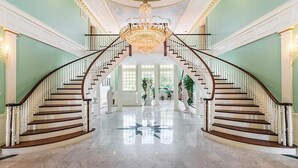 Una imponente escalera con candelabro, suelo de mármol y arquitectura clásica.
