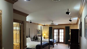 Habitación de hotel con dos camas, ventilador de techo, lámpara y ventana con cortinas.