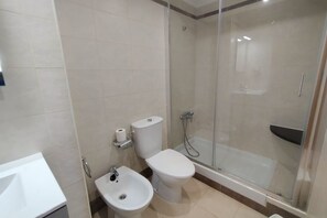 Een moderne badkamer met toilet, bidet en douchecabine.