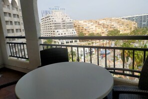 Een balkon met een ronde tafel en stoelen, met uitzicht op een stadsgezicht met meerdere gebouwen, waaronder het hotel "Hotel Marina".