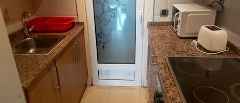 A kitchen with granite countertops, a stainless steel sink, a microwave, a toaster, and a stove.