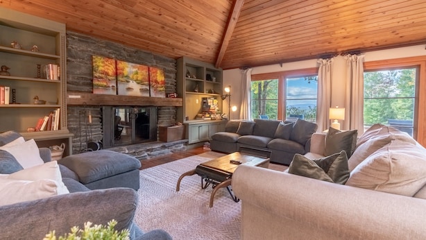 A cozy living room with a fireplace, comfortable seating, and a view of the outdoors. - Alpine Chateau Stowe-7 BR-6 bath-Game Room, Firepit, Pool! (Stowe)