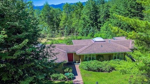 A house surrounded by dense forest with a clear sky. - Alpine Chateau Stowe-7 BR-6 bath-Game Room, Firepit, Pool! (Stowe)