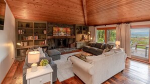A cozy living room with a fireplace, bookshelves, and a comfortable seating area. - Alpine Chateau Stowe-7 BR-6 bath-Game Room, Firepit, Pool! (Stowe)
