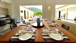 Un espace repas avec une longue table en bois dressée pour un repas, entourée de chaises.