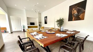 Un coin repas avec une grande table en bois, des chaises noires et un tableau accroché au mur.