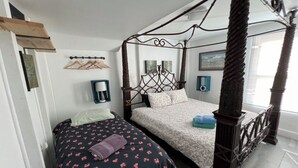 Quarto com uma cama de dossel, uma cama menor e uma mesinha de cabeceira com abajur.