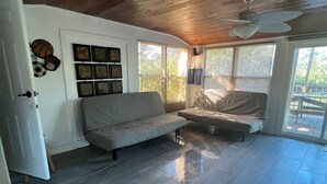Uma sala de estar ampla com teto alto, um sofá, uma mesinha e um ventilador de teto.