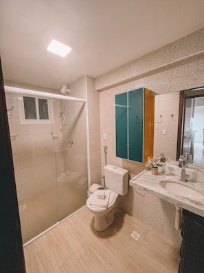 A bathroom with a toilet, shower, and sink. - Apartamento Praia do Cumbuco (Caucaia)