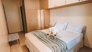 A bedroom with a bed, a small table with a lamp, and built-in wardrobes. - Apartamento Praia do Cumbuco (Caucaia)