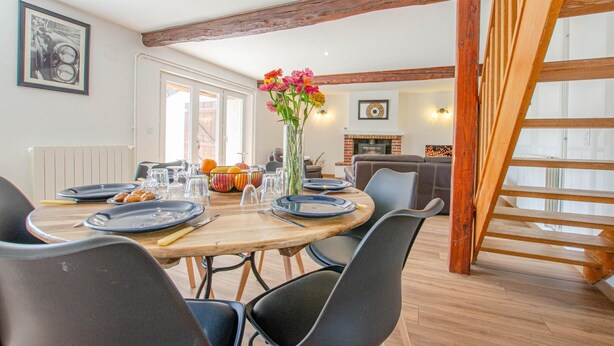 A dining area with a wooden table set for four, surrounded by chairs, and a vase with flowers on the table. - L'Escale Champenoise (PLESSIS BARBUISE)