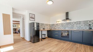 A modern kitchen with a stainless steel refrigerator, dark cabinets, and patterned backsplash tiles. - L'Escale Champenoise (PLESSIS BARBUISE)