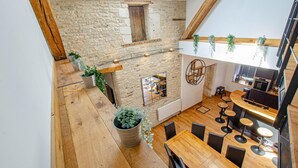 A modern kitchen with a stone wall, wooden flooring, and a bar area with stools.