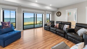 A spacious living room with a view of the sea, a blue sofa, and leather couches. - An amazing large group vacation home with elevator and breathtaking views. (Montross)