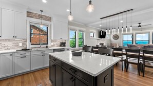 A modern kitchen with white cabinets, a large island, and pendant lighting. - An amazing large group vacation home with elevator and breathtaking views. (Montross)