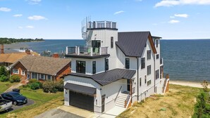 A two-story house with a garage, a balcony, and a view of the water. - An amazing large group vacation home with elevator and breathtaking views. (Montross)