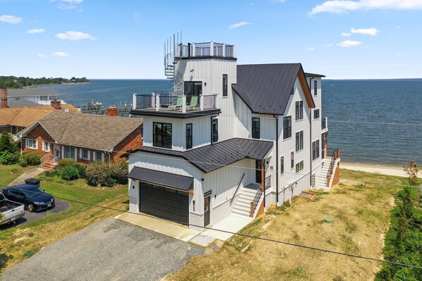 A two-story house with a garage, a balcony, and a view of the water.