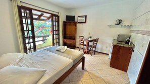Een slaapkamer met een bed, bureau en een kitchenette.