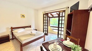Una habitación de hotel con una cama, una mesa lista para comer y un amplio ventanal con puerta abierta.