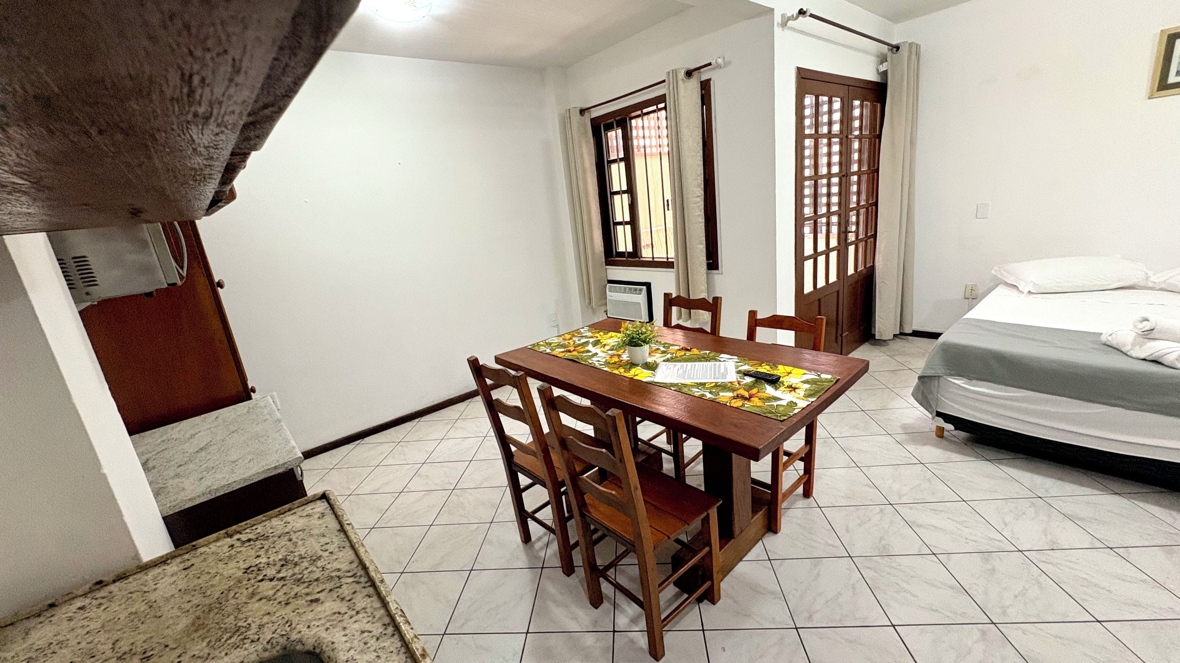 Una habitación con una mesa de comedor, sillas, una cama y una ventana con cortinas.