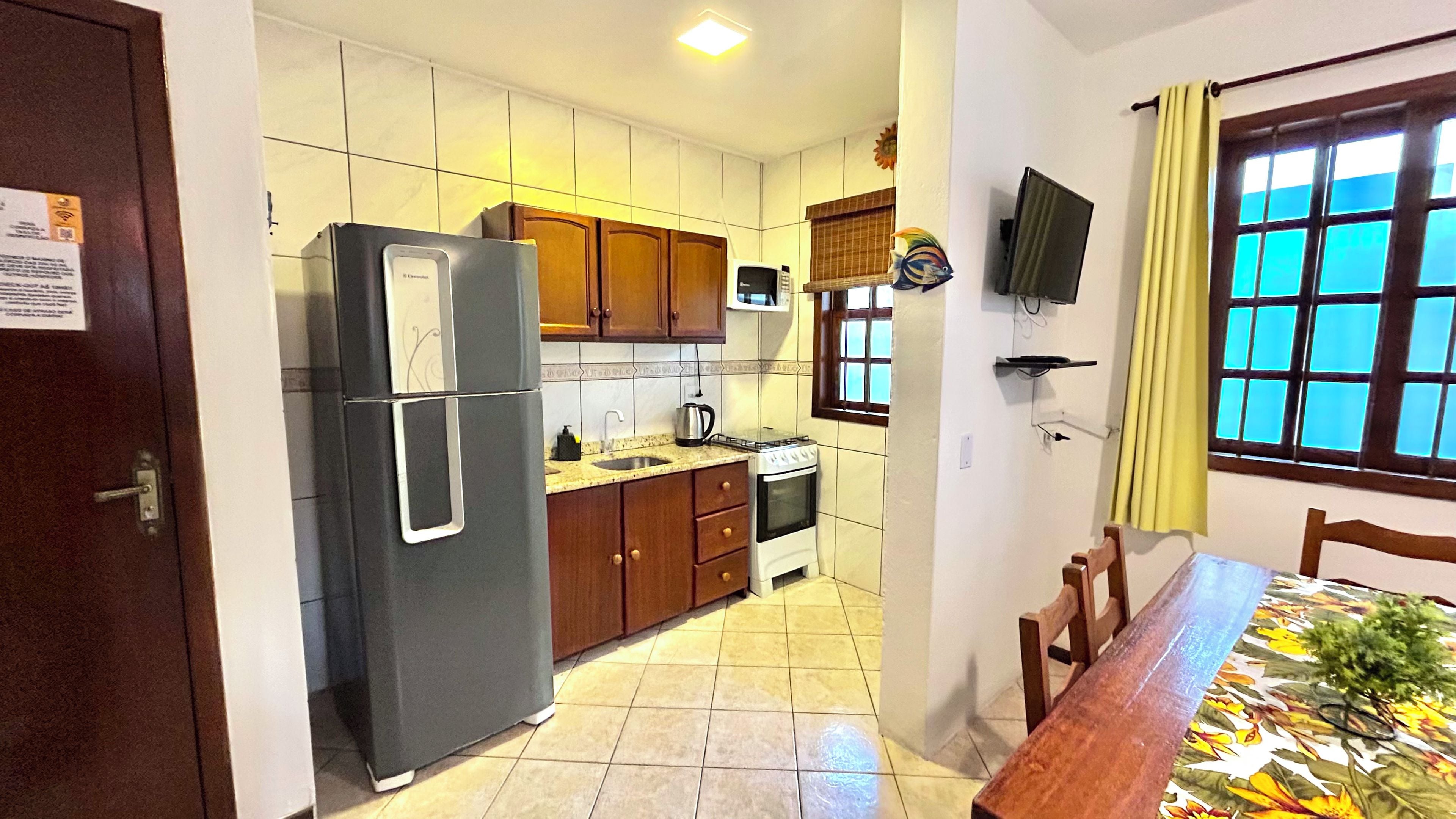 Una cocina compacta con refrigerador, estufa, microondas y gabinetes de madera.