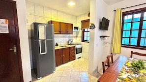 Una cocina compacta con refrigerador, estufa, microondas y gabinetes de madera.
