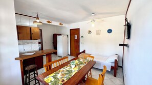 A compact kitchen with a dining area, wooden furniture, and a ceiling fan. - Pousada Jardim das Gales Bombinhas (Bombinhas)