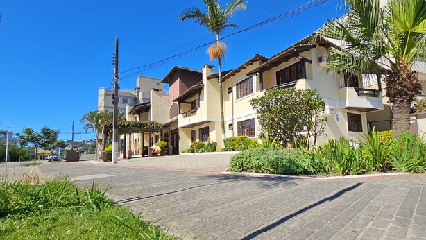 A residential building with multiple balconies, a paved driveway, and lush greenery including palm trees and shrubs. - Pousada Jardim das Gales Bombinhas (Bombinhas)
