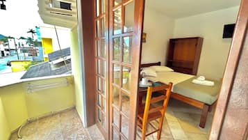 A compact room with a bed, a small table, and a chair. There is a window with a view of the outside.