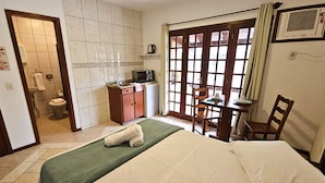 Hotelkamer met een bed, een klein tafeltje met stoelen, een magnetron en uitzicht door een schuifdeur.