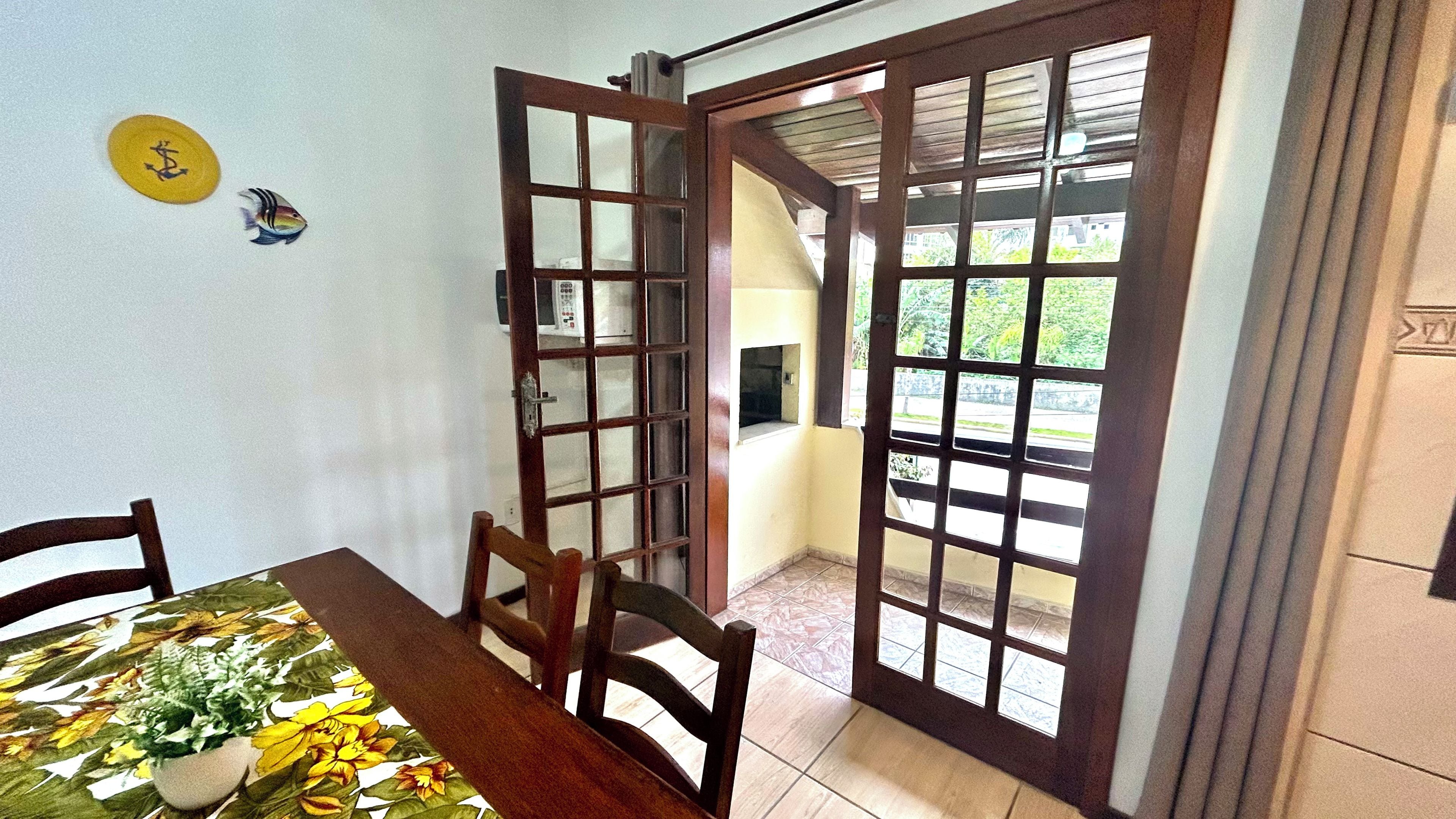 Un comedor con una mesa, sillas, una planta en maceta y una puerta con paneles de vidrio.
