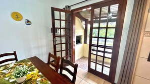 Een eetruimte met een tafel, stoelen, een potplant en een deur met glaspanelen.