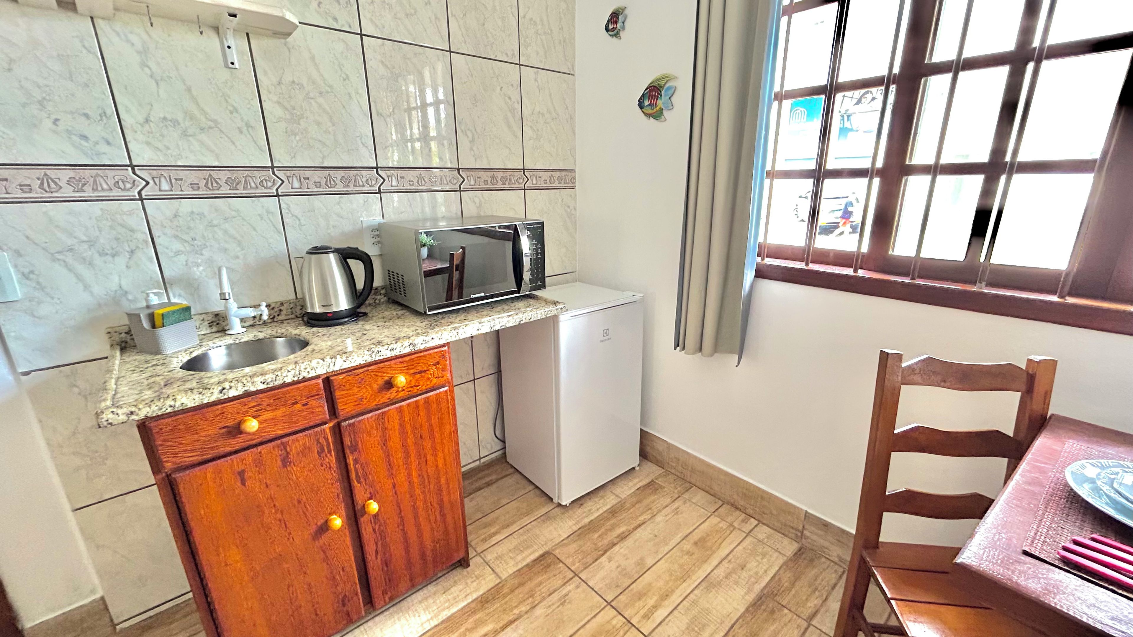 Een kleine keuken met een magnetron, waterkoker en een kleine koelkast.