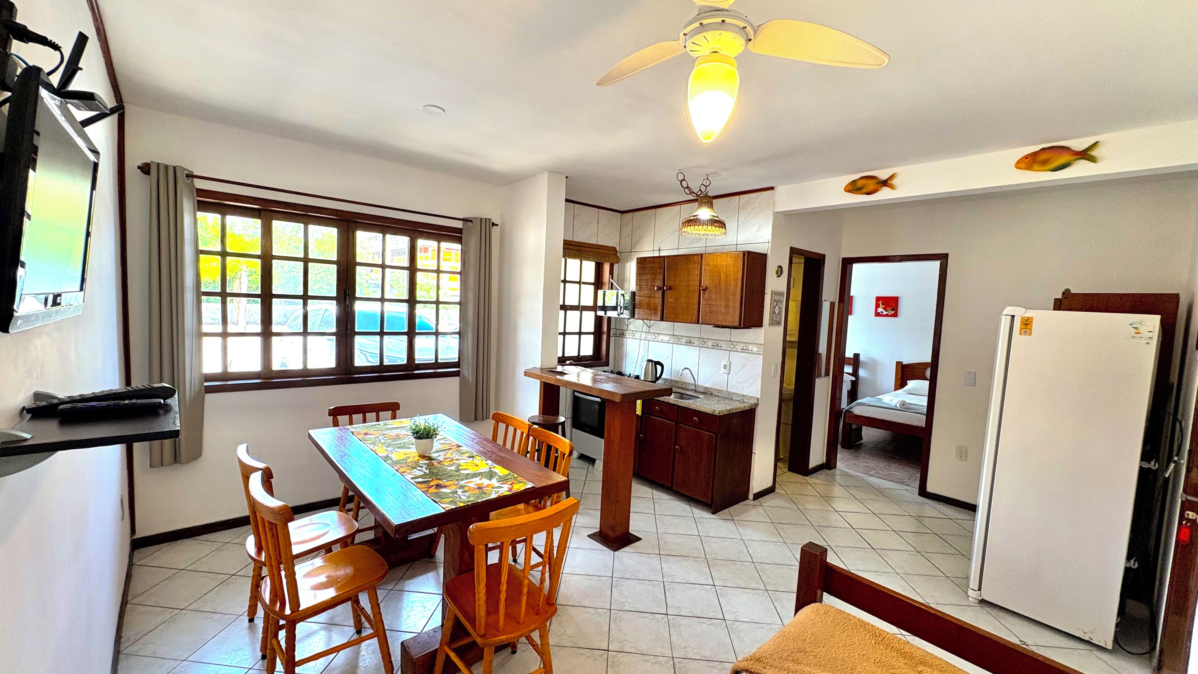 A compact kitchen with a dining area, a refrigerator, and a ceiling fan.